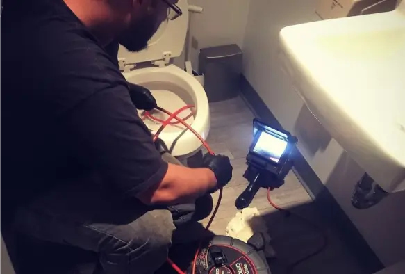 Plumber using fiber optic camera to inspect toilet and drainpipe