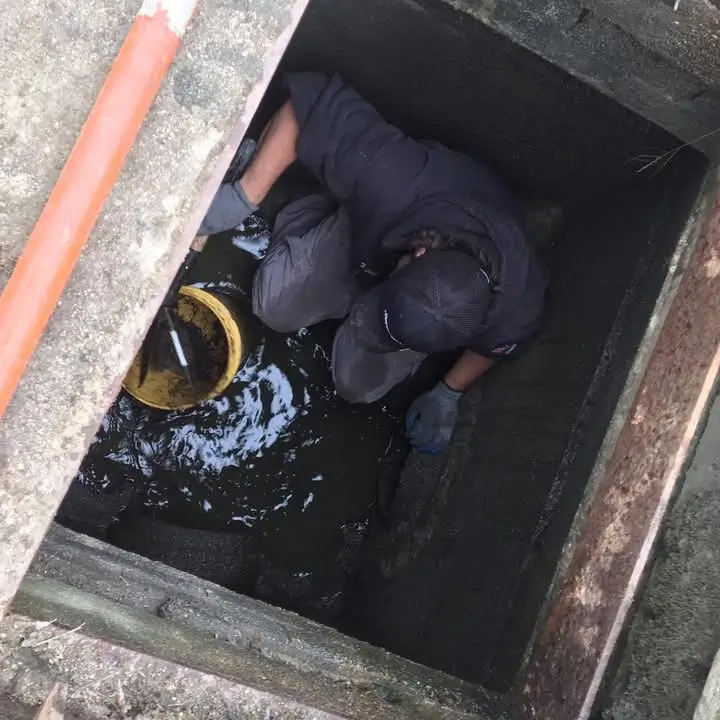 Plumber inspecting sewer line in Groton, CT, with drain cleaning tools.