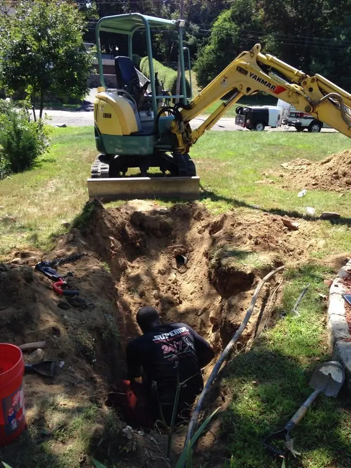 Excavator and worker repairing sewer line in Mystic, CT.