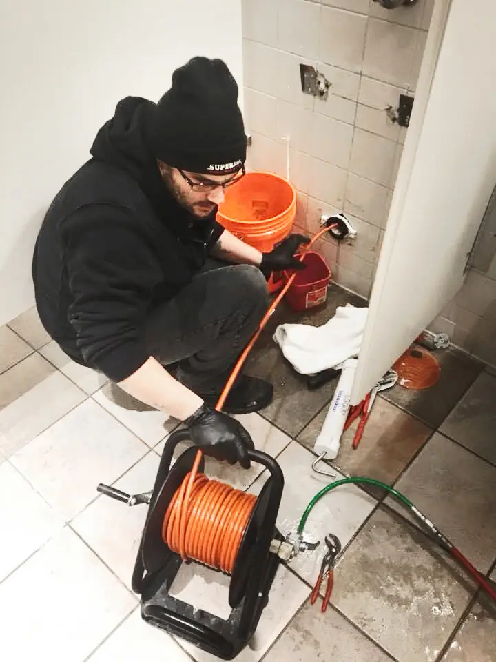 Plumber repairing sewer line with drain cleaning tools and equipment.